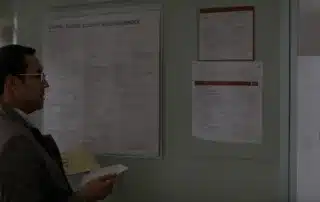 a doctor reviews a medical chart in a clinic with various health and safety posters on the wall.